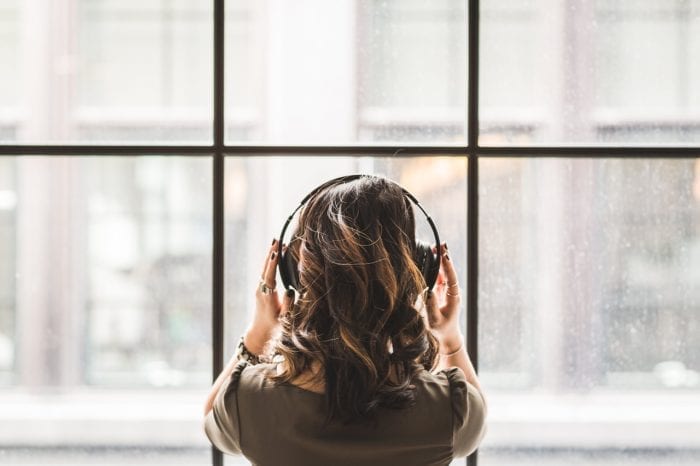 employee stares out of the window while listening to curated music with headphones