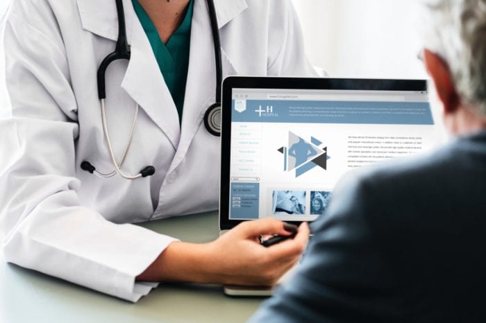 Doctor explaining a healthcare website on a laptop to a patient