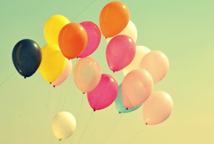 Several colorful balloons on strings floating in the air