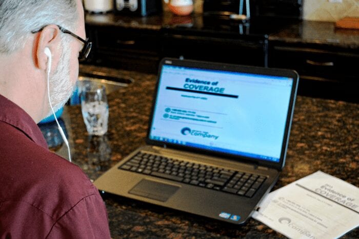 A man sitting in front of his laptop computer listening to a 508 Compliant accessible PDF document with Screen Reading software.
