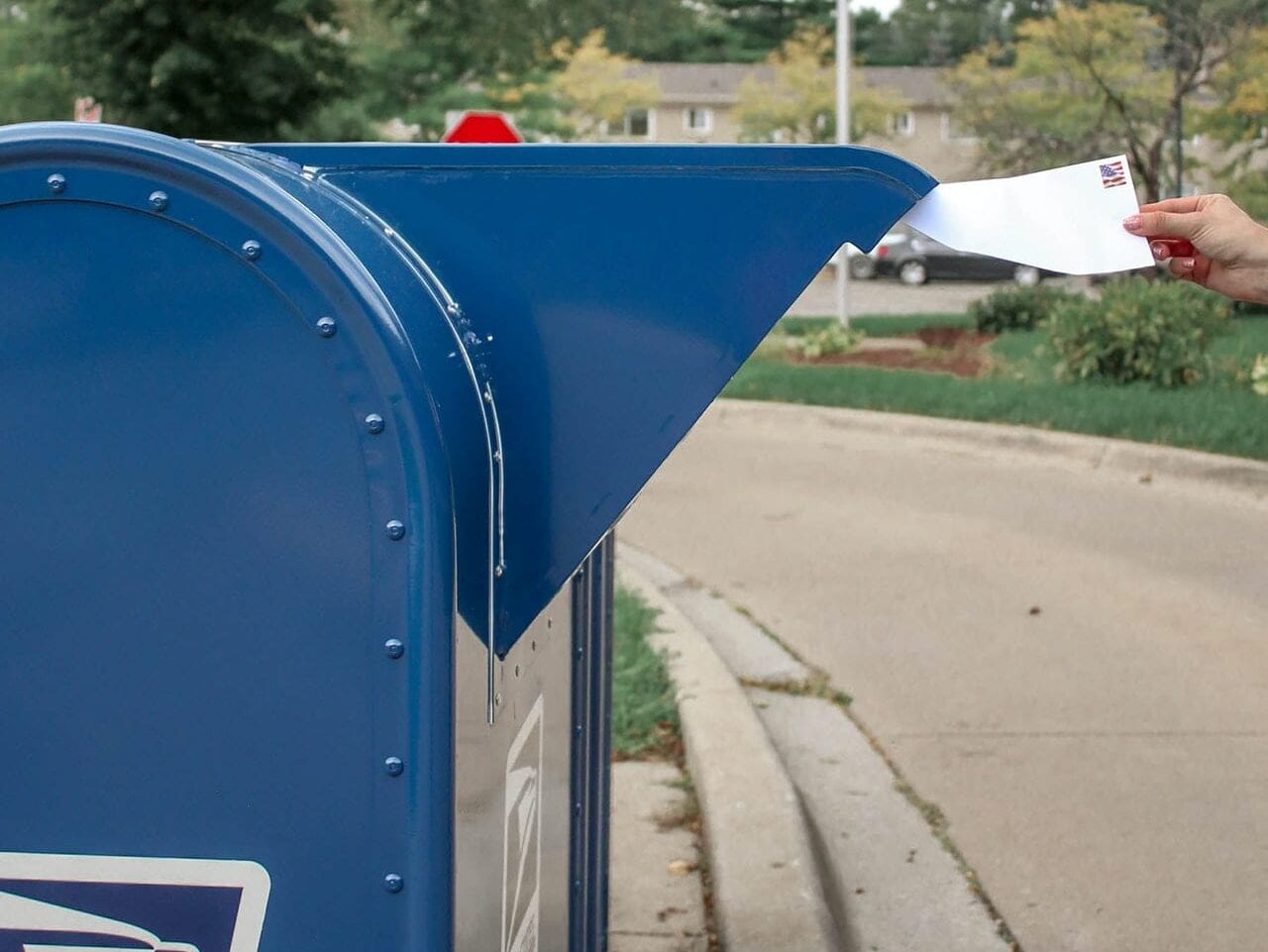 An American voter putting their accessible ballots in a mailbox.