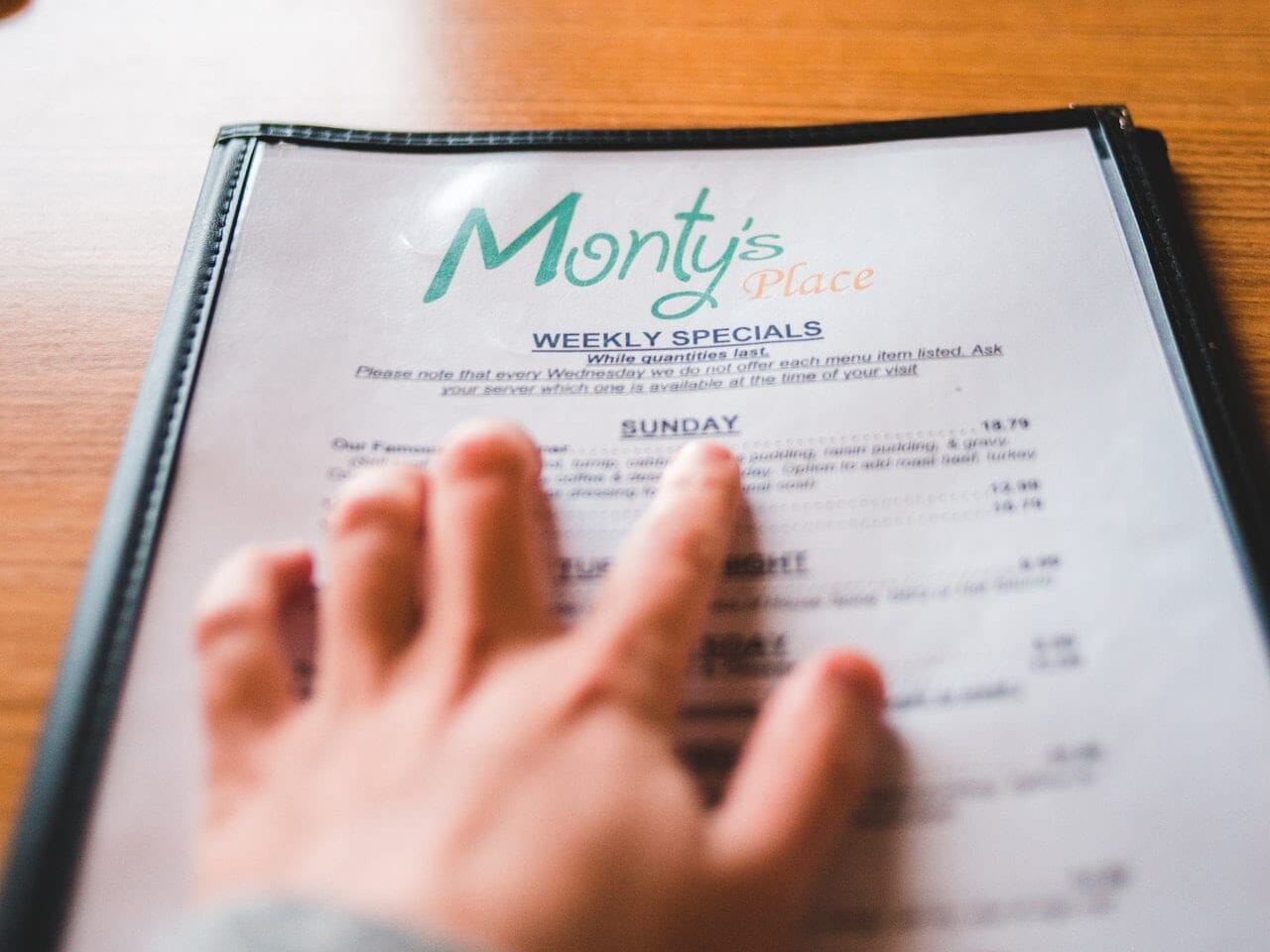 a hand scrolling across items on disposable menus
