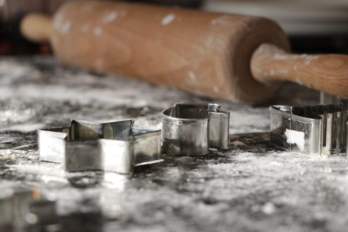 flour on a countertop along with a rolling pin and cookie cutters