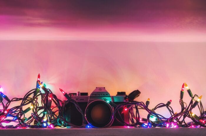 Camera on a shelf surrounded by Christmas lights