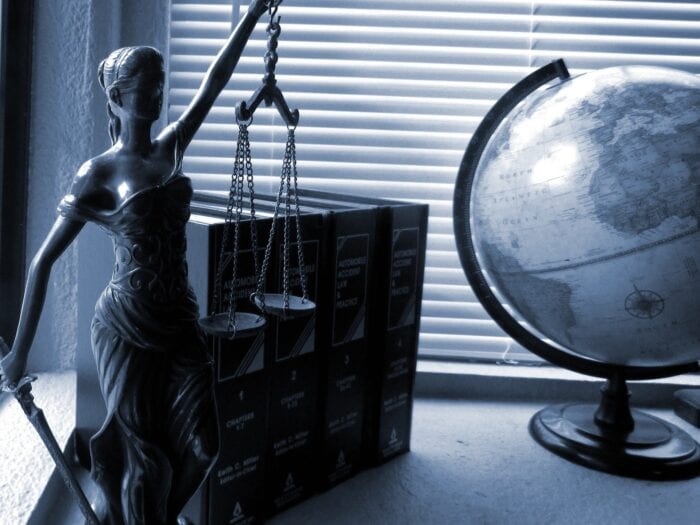 Statue of lady liberty, 4 law books, and a globe next to a window with closed mini blinds