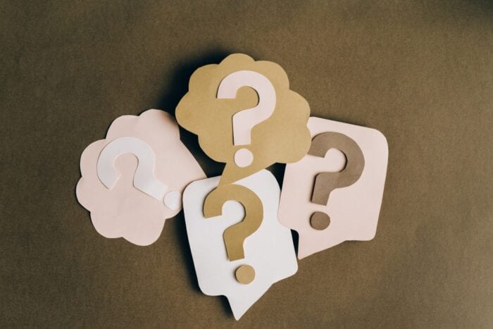 Paper question marks on top of paper speech bubbles