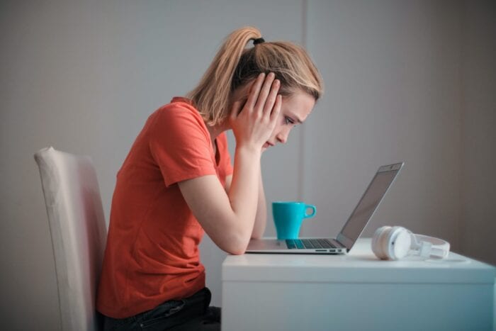 Frustrated girl holding her head while looking at a laptop