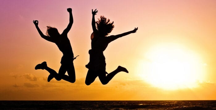 2 women jumping in celebration in front of sunset