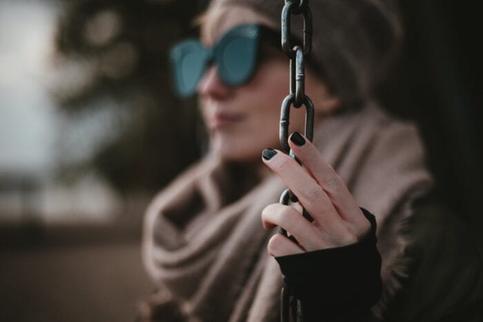 Woman wearing sunglasses holding onto a vertical chain