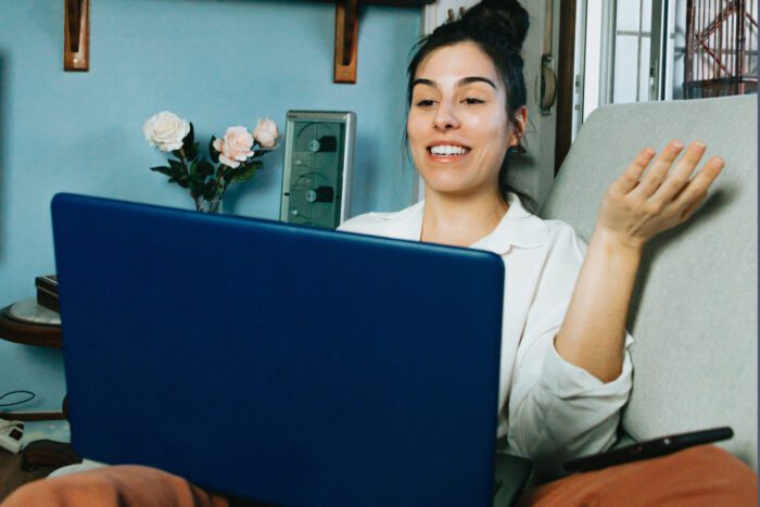 Woman at home looking at her laptop while smiling and shrugging