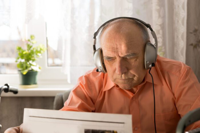 Elderly man listening to audio on a computer with headphones