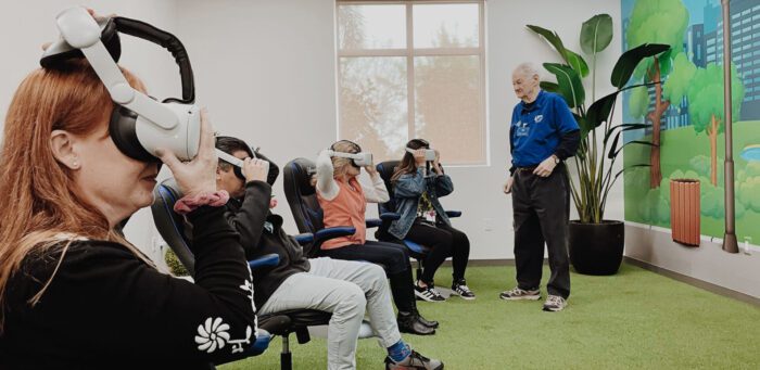 Four people put on their virtual reality headsets while a gentleman gives instructions