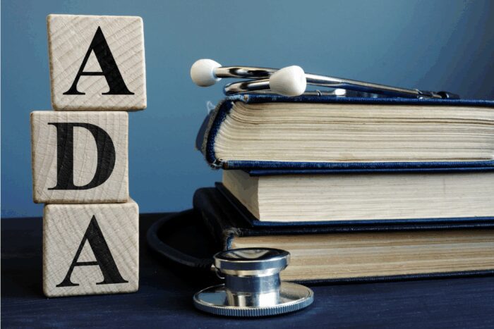 Wooden blocks stacked together to spell out. ADA. Next to it is a stack of books with a stethoscope on top of it.