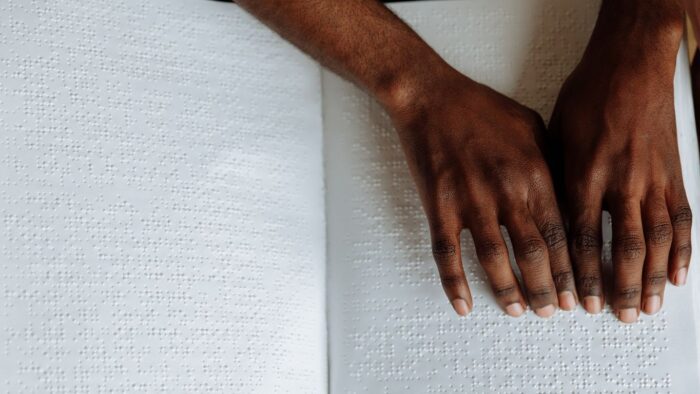 Hands reading a paper braille book