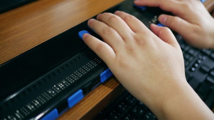Hands reading electronic braille on a refreshable braille display