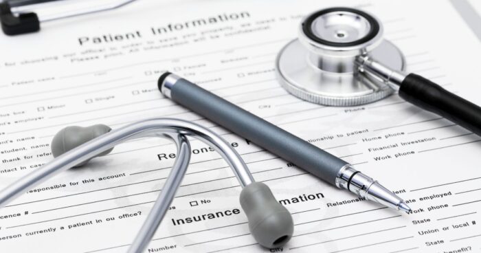 A paper Patient Information form with small print on a clipboard with a pen and stethoscope on top