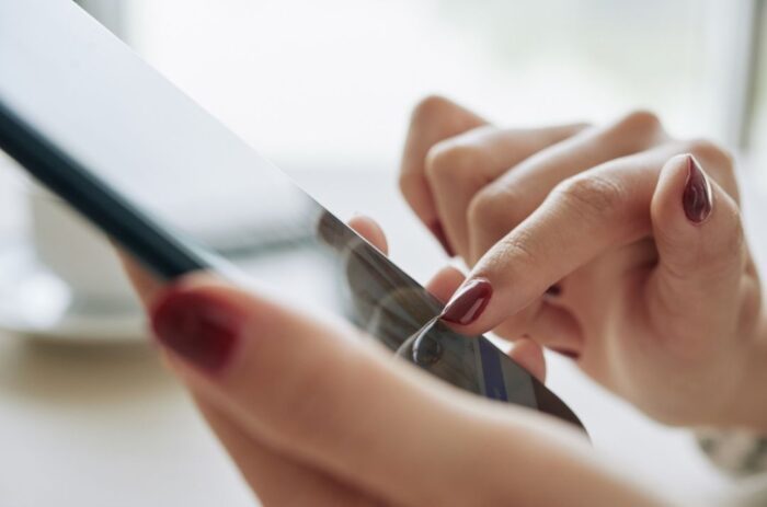 Someone holding a phone and touching the screen with their finger.